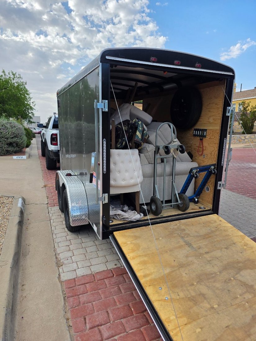 Staging trailer loaded with furniture and a dolly at the curb