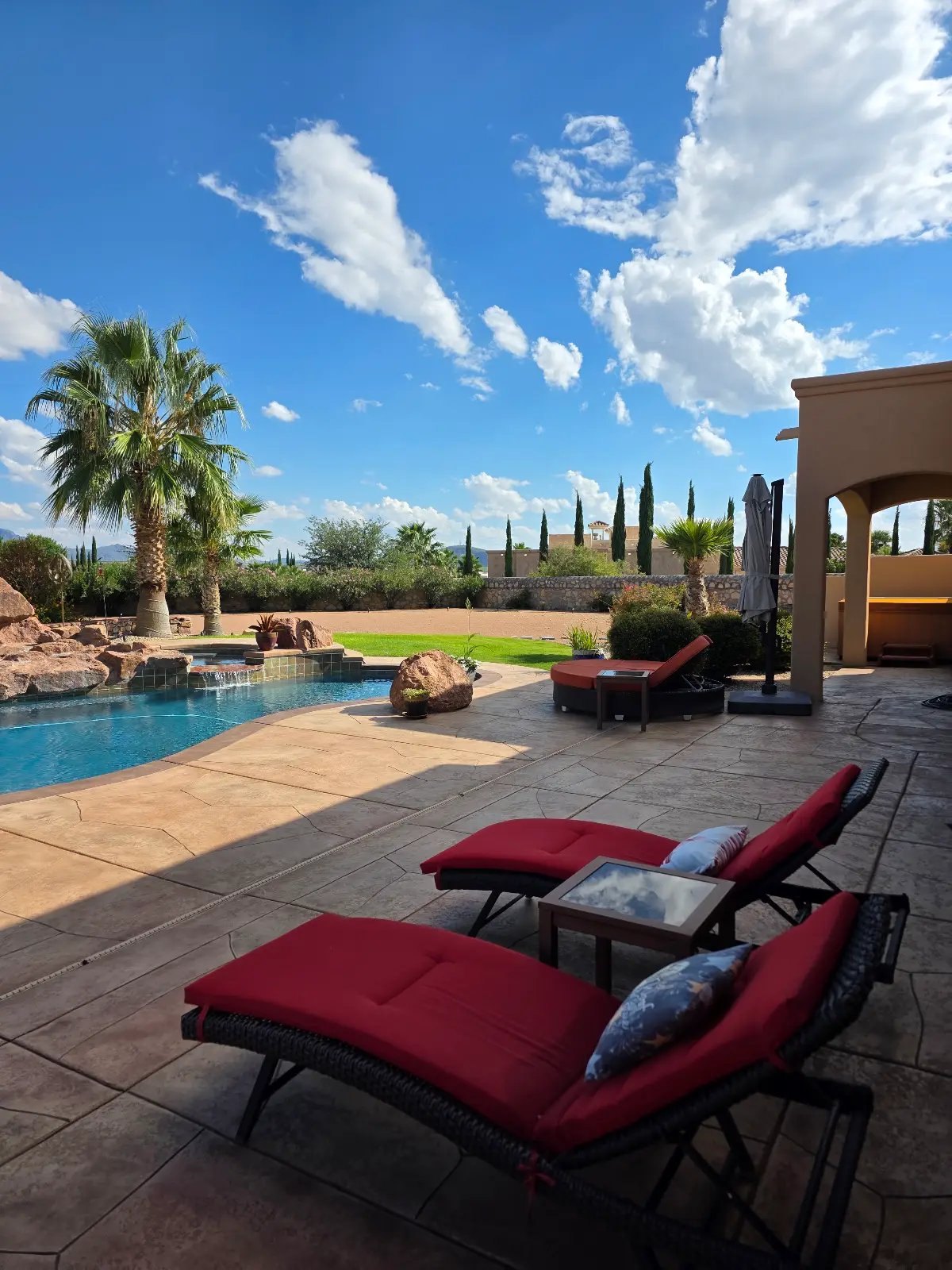 Red loungers staged beside a pool, outdoor living staging Las Cruces